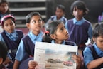 shallow focus photo of girl holding newspaper