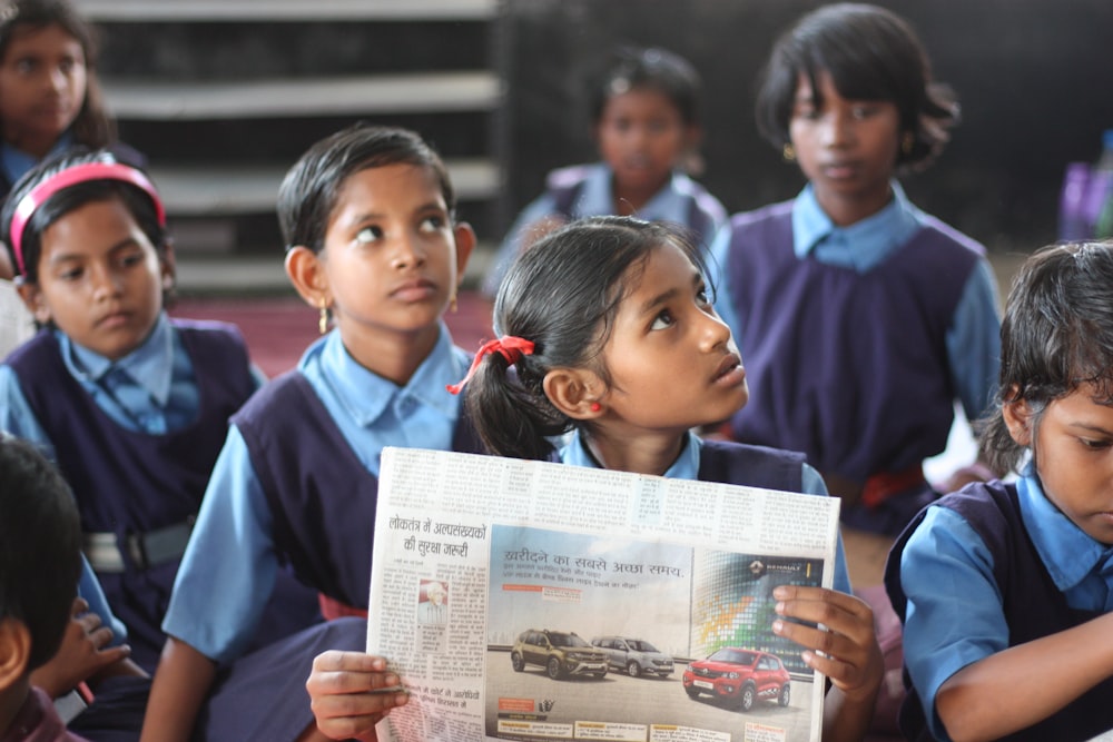 shallow focus photo of girl holding newspaper