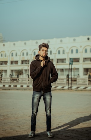 Model posing confidently outdoors wearing a sleek Caos black hoodie with red logo.