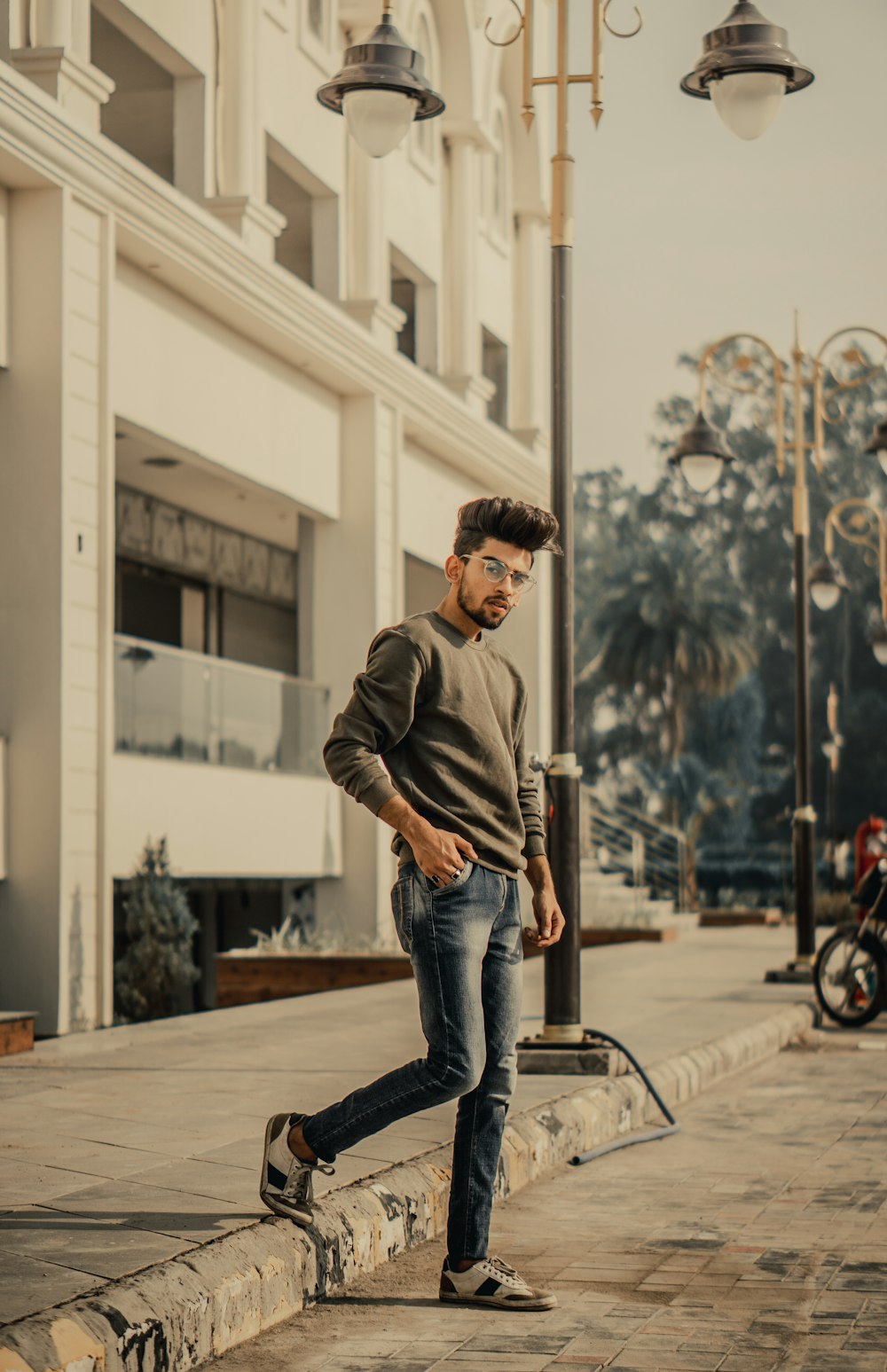 man wearing black crew-neck sweater standing near white building