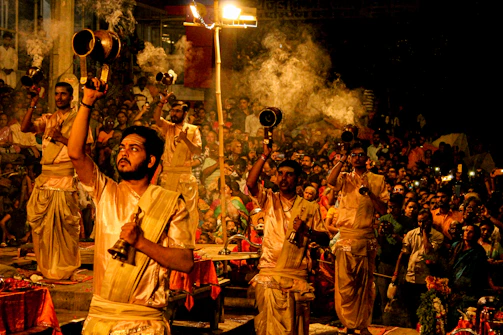A serene evening aarti with devotees holding incense sticks and lamps.