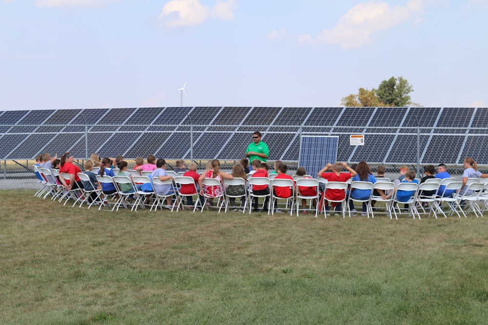 a group of people sitting in chairs in front of a solar panel