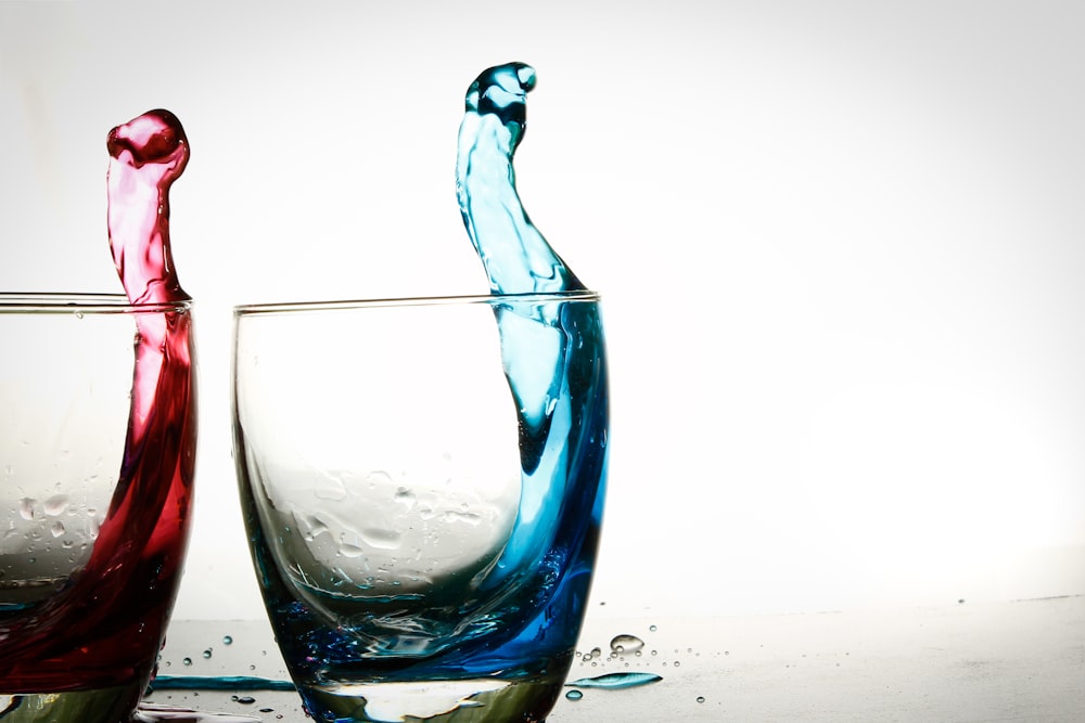 two clear drinking glasses with red and blue liquids