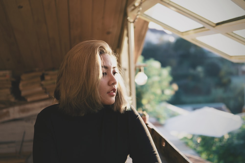 woman wearing black crew-neck long-sleeved shirt glancing her left side