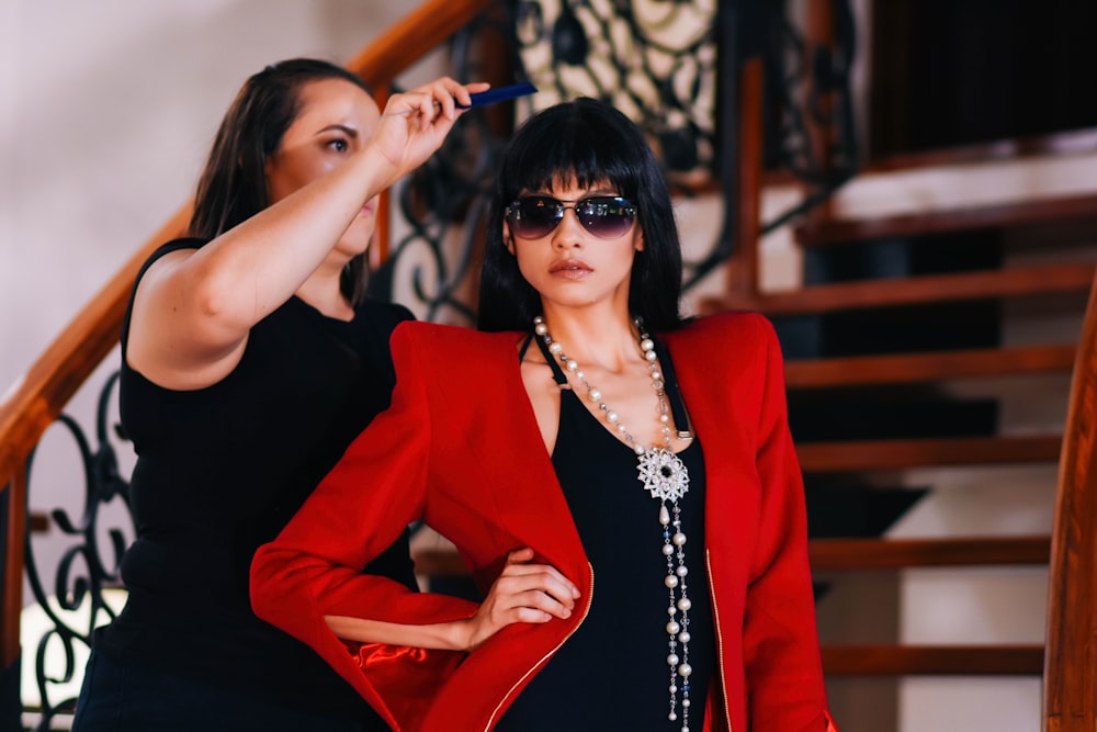 woman about to comb the hair of woman wearing red blazer