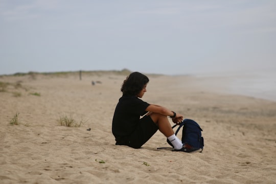 person in black shirt sitting on beach in Esposende Portugal