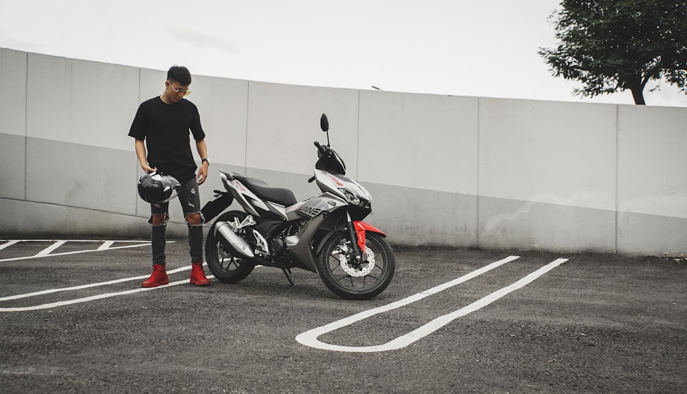 man standing beside motorcycle on parking lot