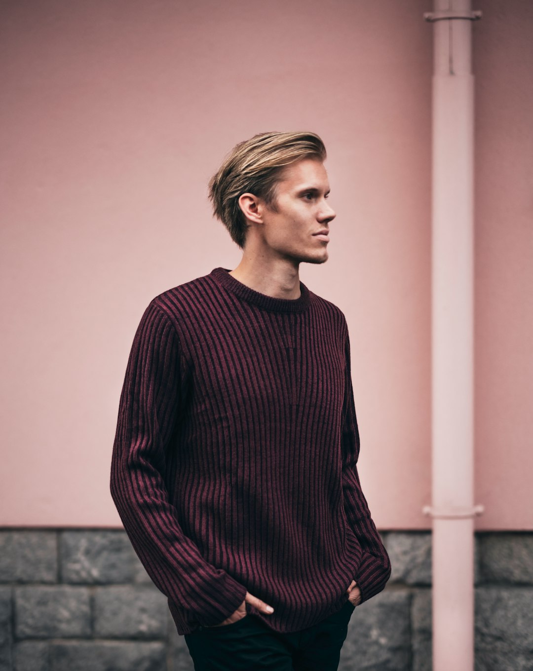 man in brown sweater standing beside wall