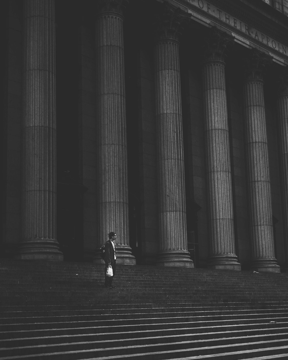 grayscale photography of man standing near concrete building