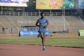 A male athlete sprinting on a track stadium under bright lights.