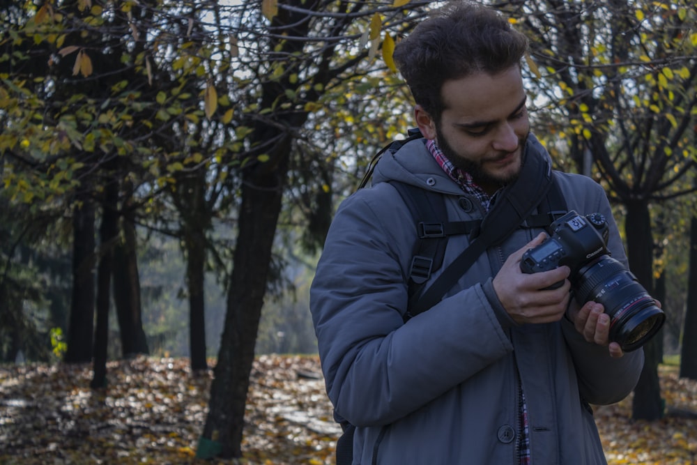 man holding DSLR camera in forest during daytime