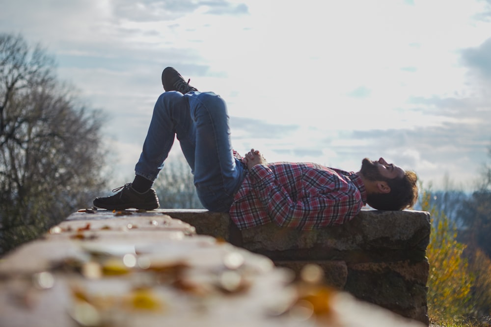 man lying on gray concrete handrail