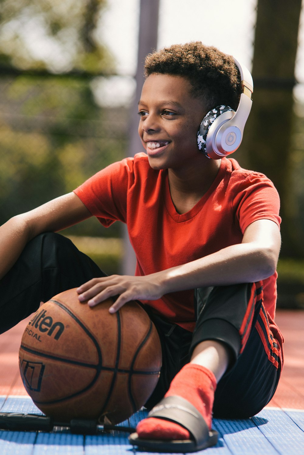 selective focus photography of smiling boy wearing headphones and holding basketball