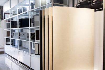 A display area in a showroom with vertical panels leaning against a shelving unit filled with color and material samples. The shelving is organized with various swatches and sample boards.