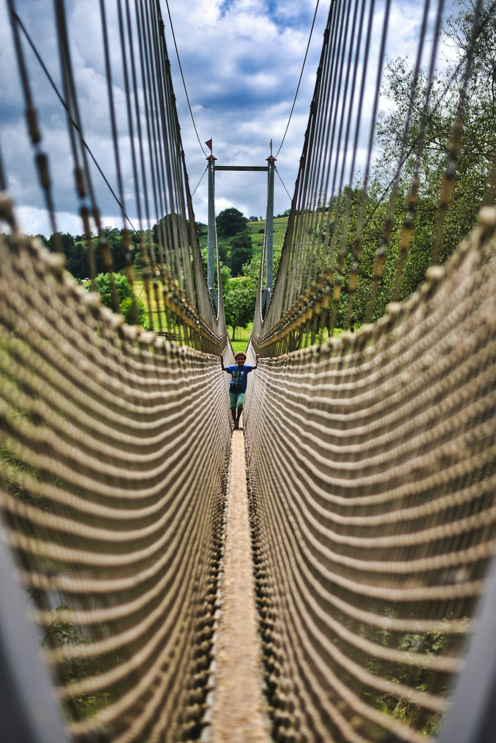 白と青の空の下、茶色の歩道橋の上に立つ人