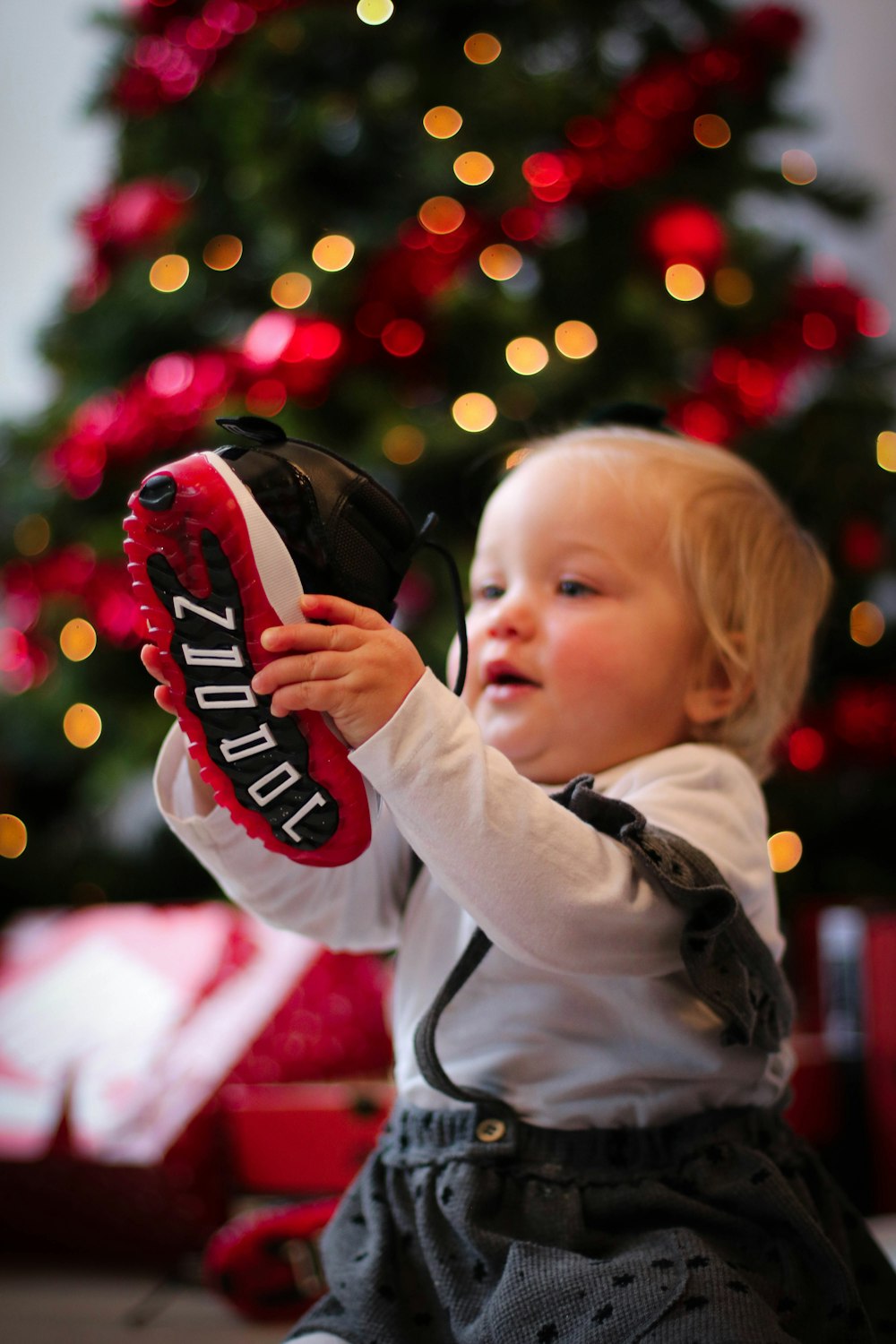 child in white and black hoodie holding red and black headphones