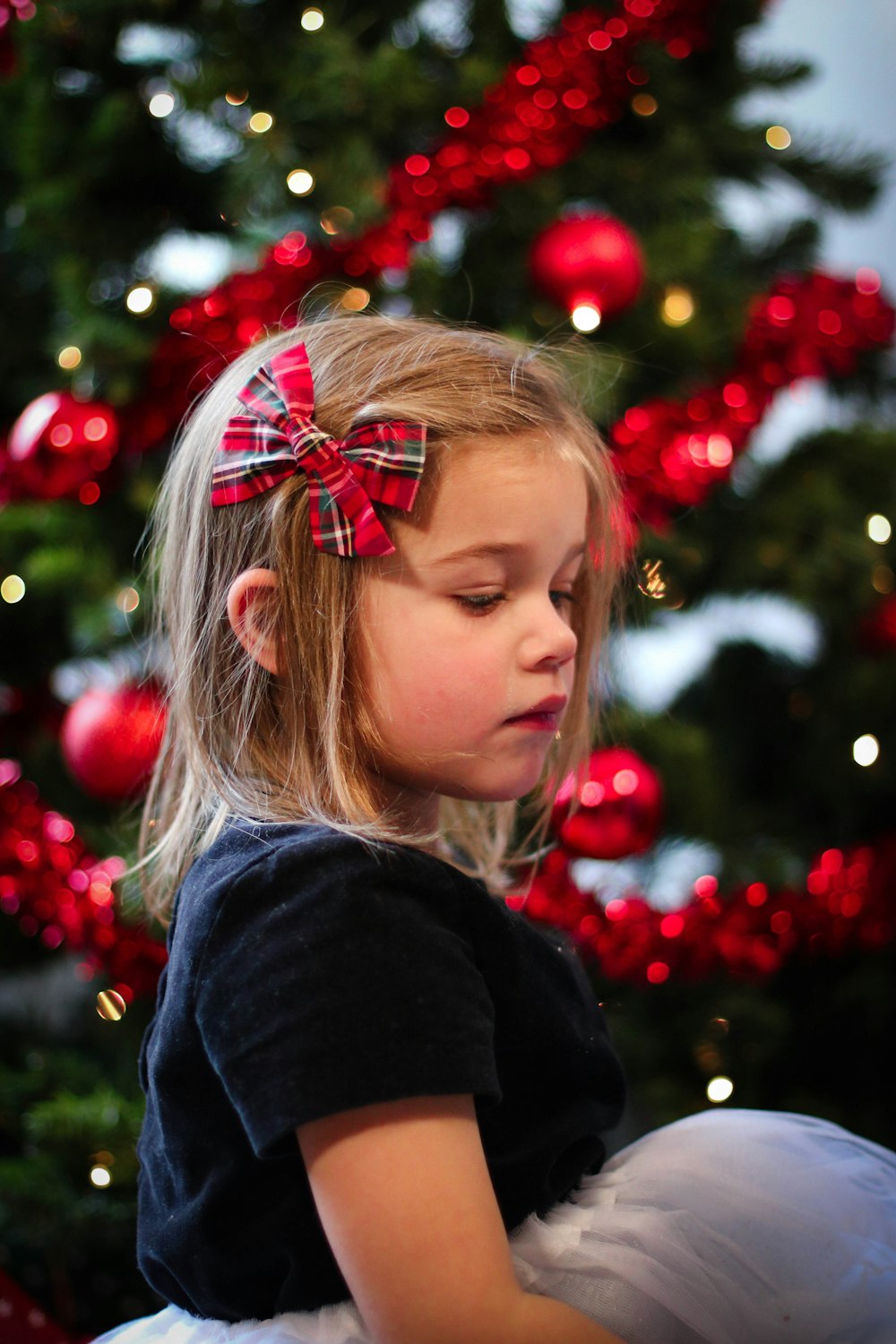 girl in black sweater with red and green ribbon on her head