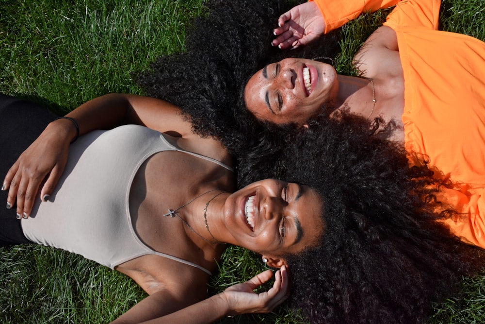 two women lying on green grass