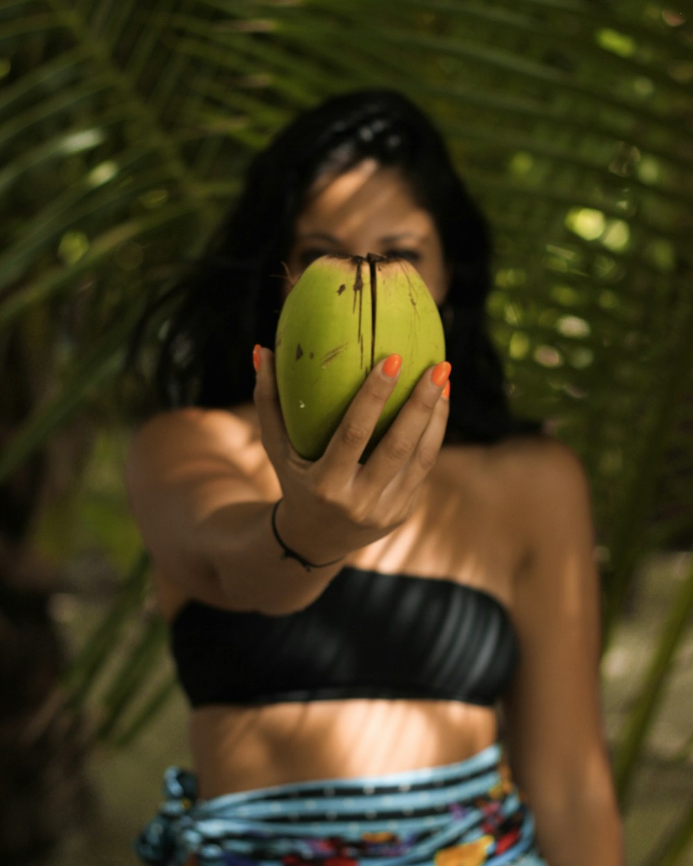 woman wearing black bandeau standing while holding green coconut