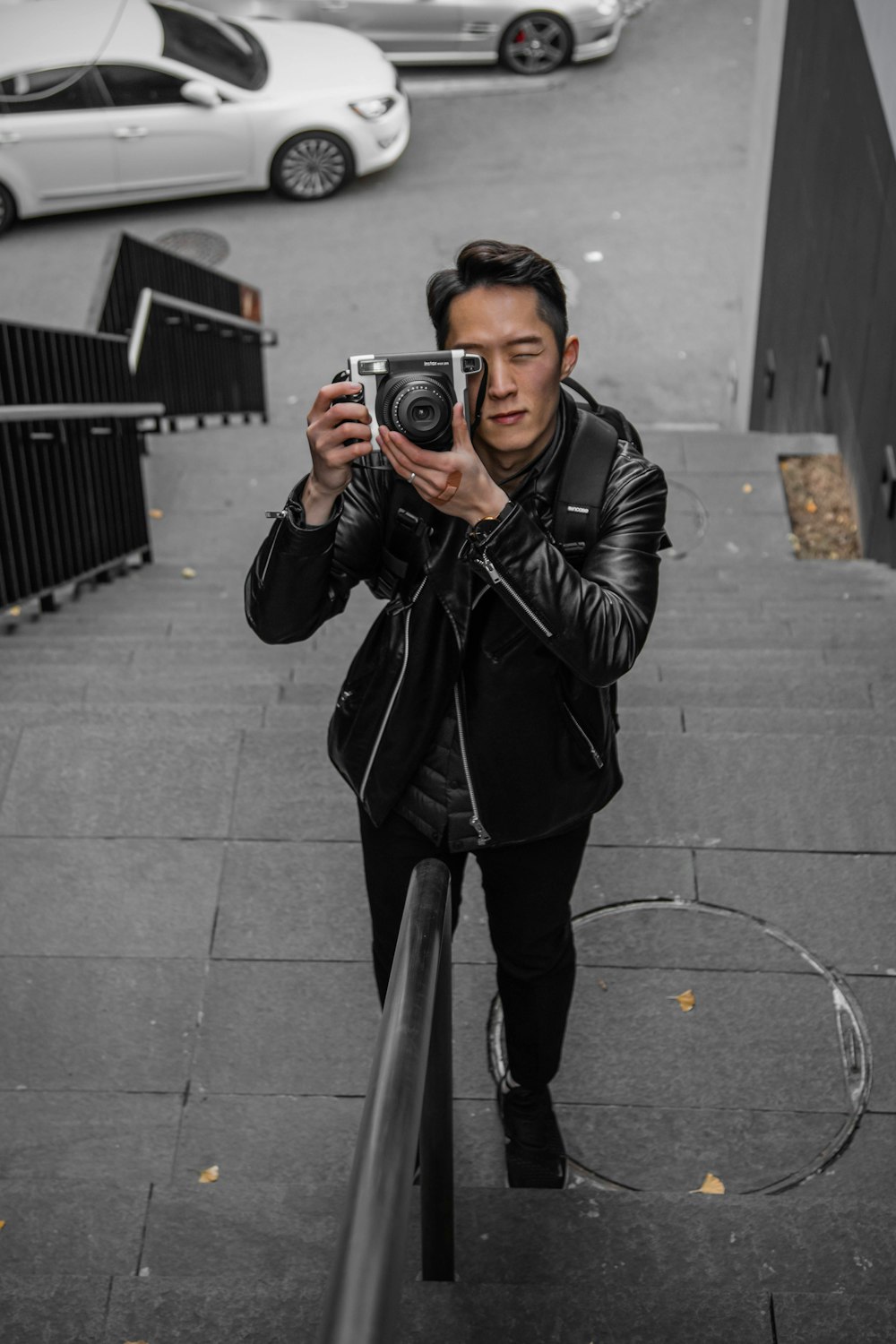 shallow focus photo of man in black leather jacket using camera