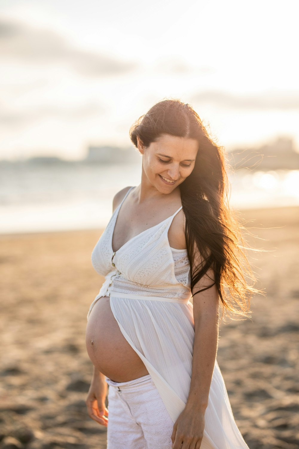 pregnant woman standing on the beach sand