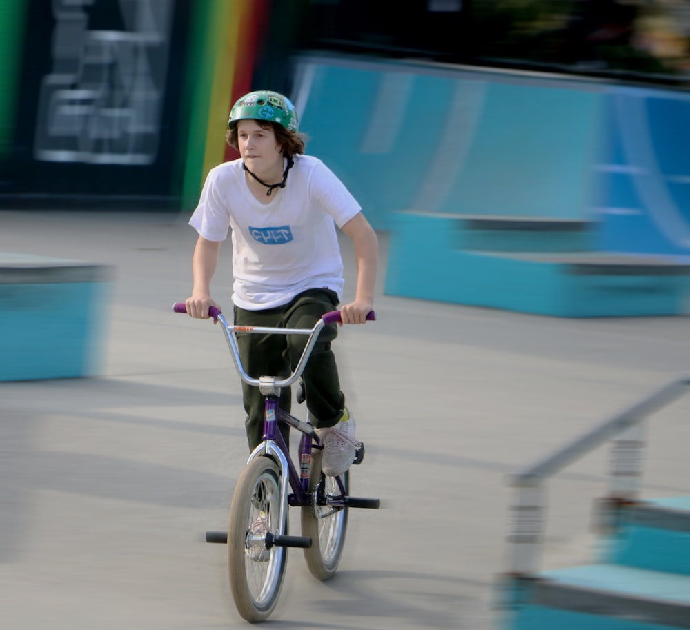 shallow focus photo of boy in white crew-neck T-shirt riding BMX bike