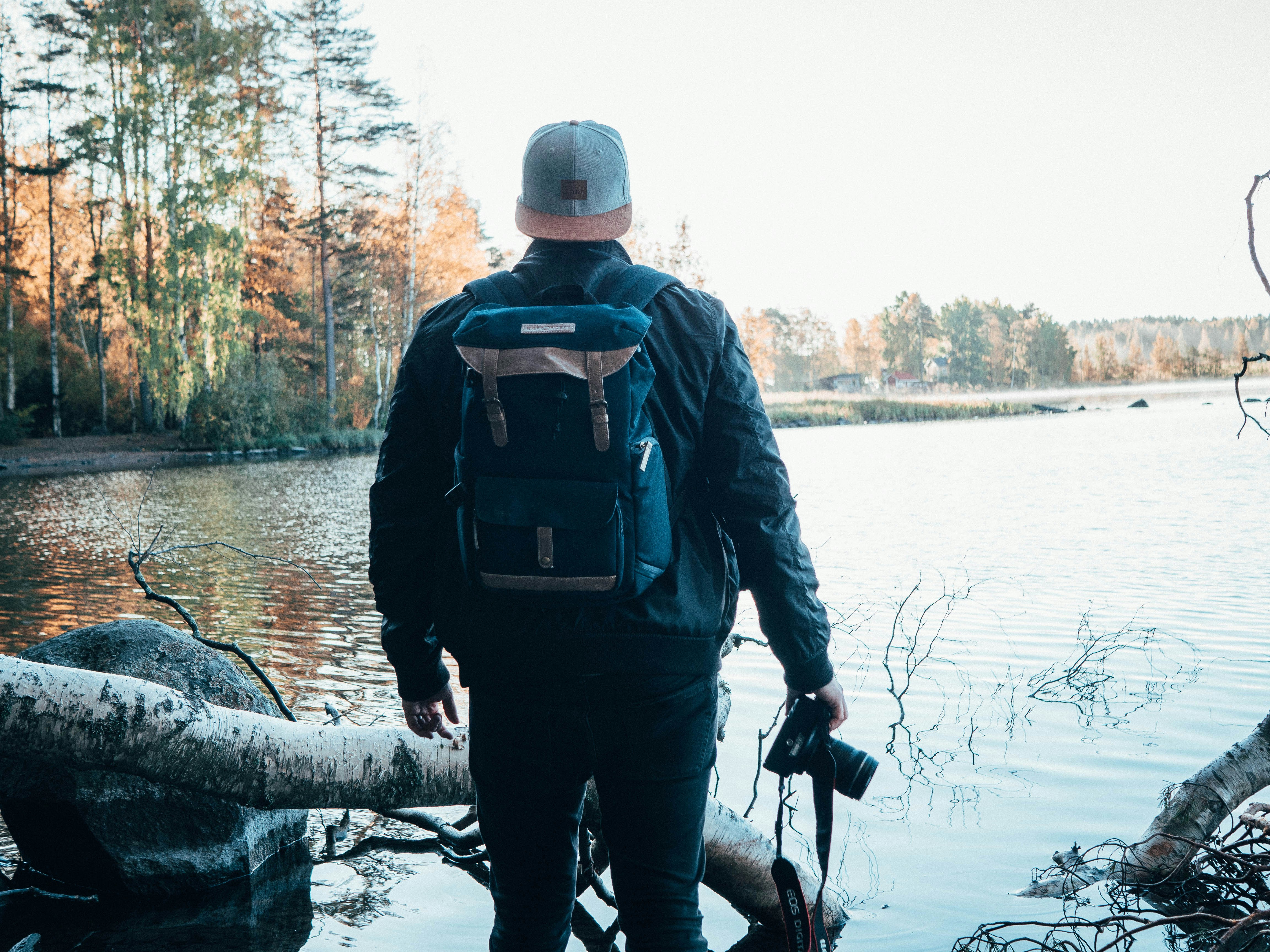 shallow focus photo of person in blue jacket holding DSLR camera