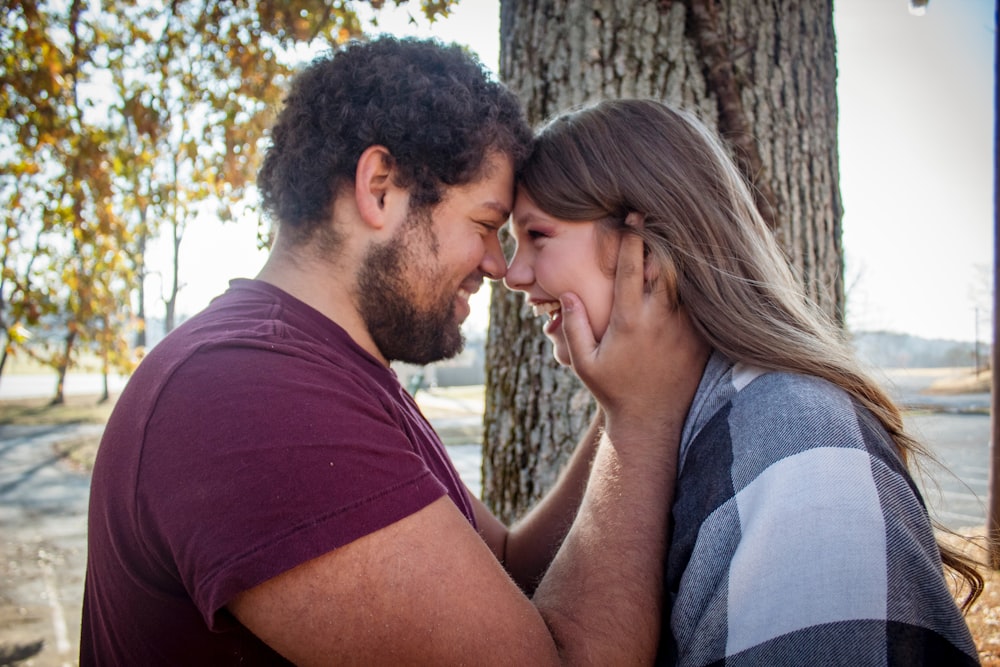 man and woman standing face to face near tree