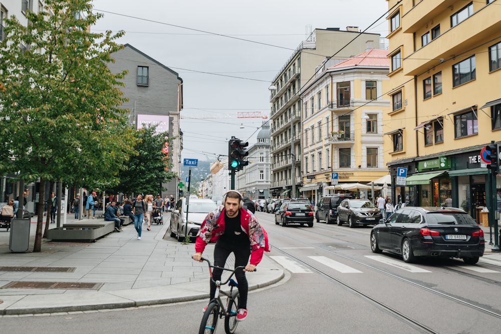 man riding on bike in the middle of the street near vehicles beside building