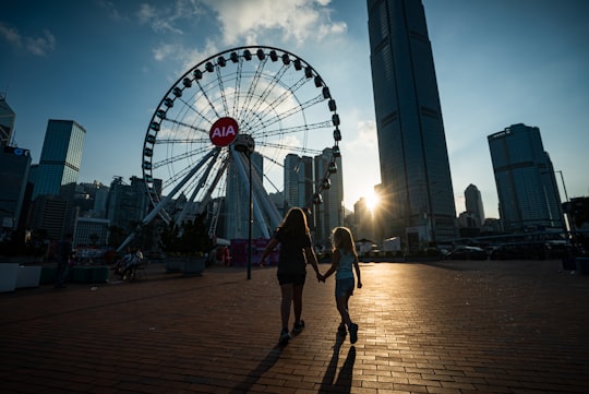 people near buildings and Ferris wheel during day in Victoria Harbour Hong Kong
