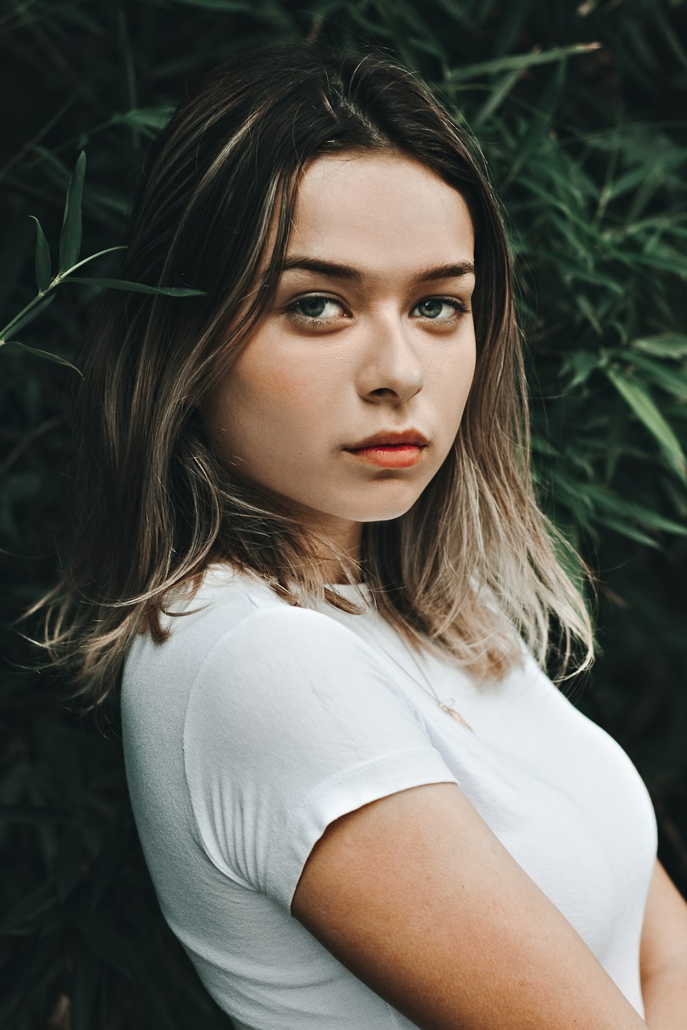 woman wearing white crew-neck t-shirt standing near green leaf plant