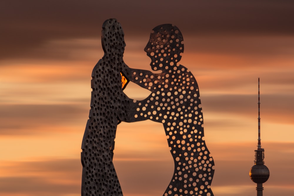 ゴールデンアワーの立っている2人の男性の像のシルエット