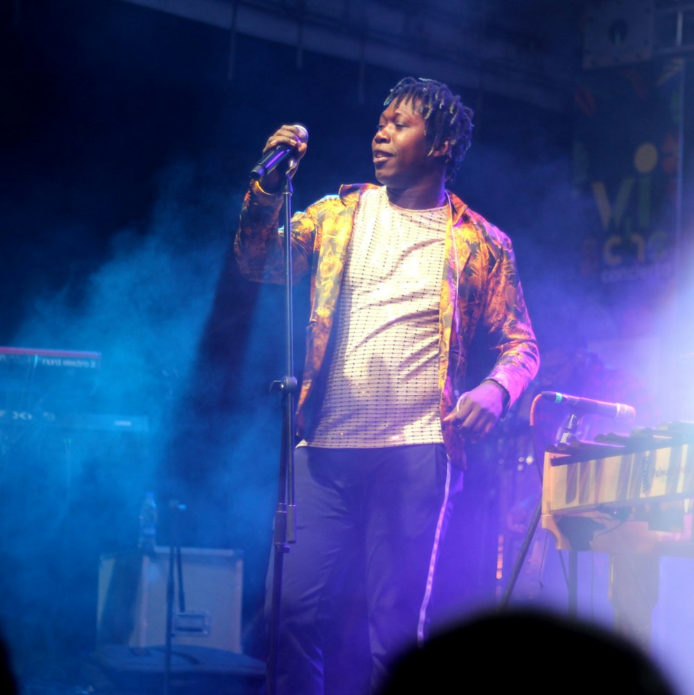 man in yellow and pink full-zip jacket holding wireless microphone