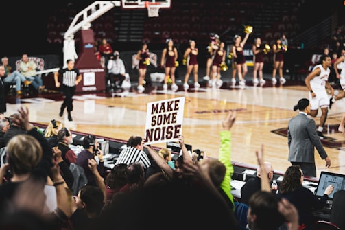 An action shot from a local high school basketball game, fans cheering in the stands.
