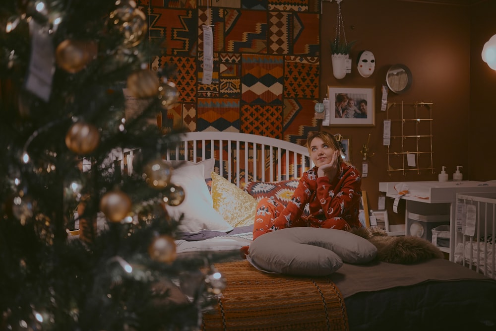 mulher sentada na cama perto da árvore de Natal