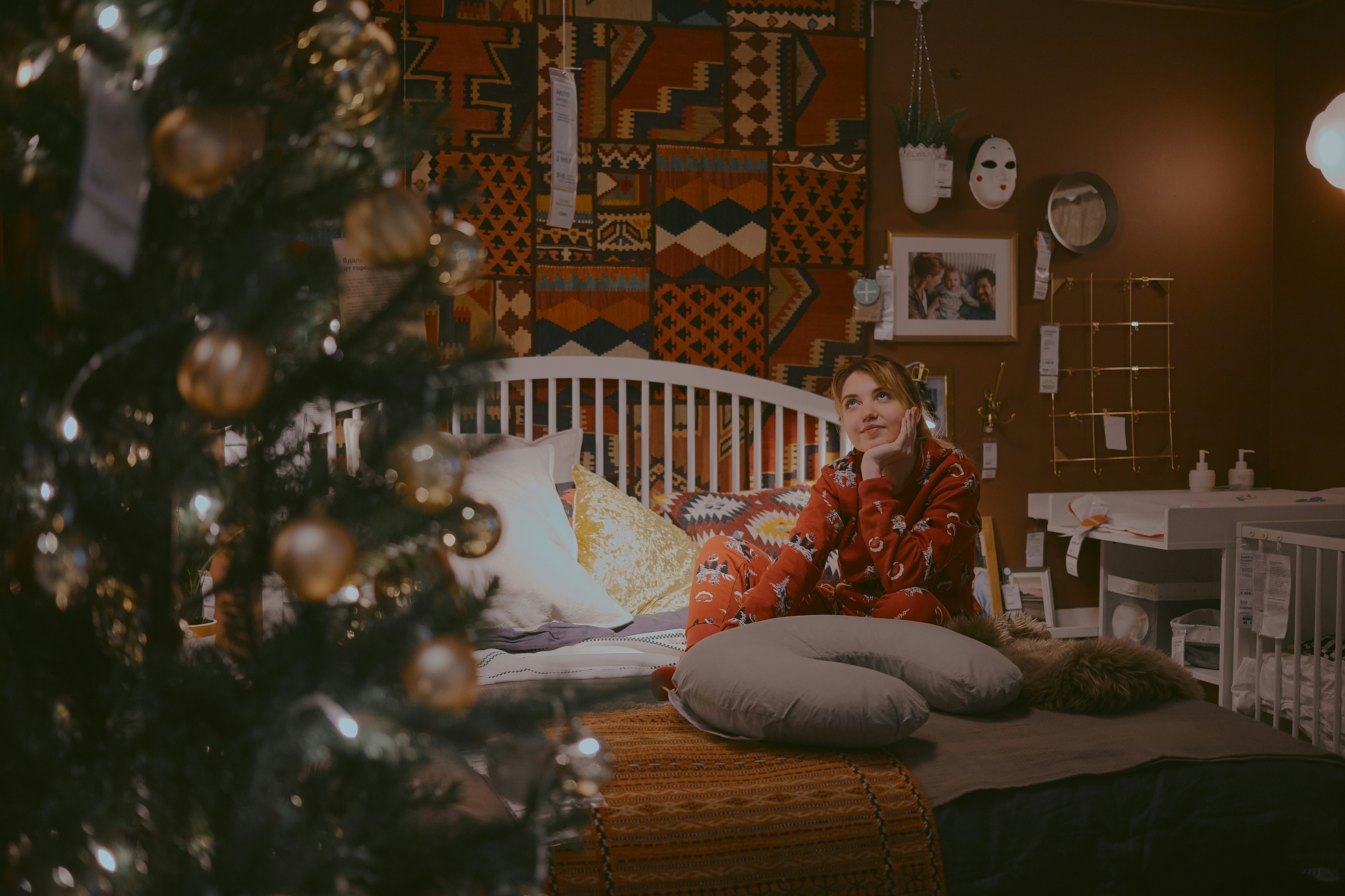 woman sitting on bed near Christmas tree