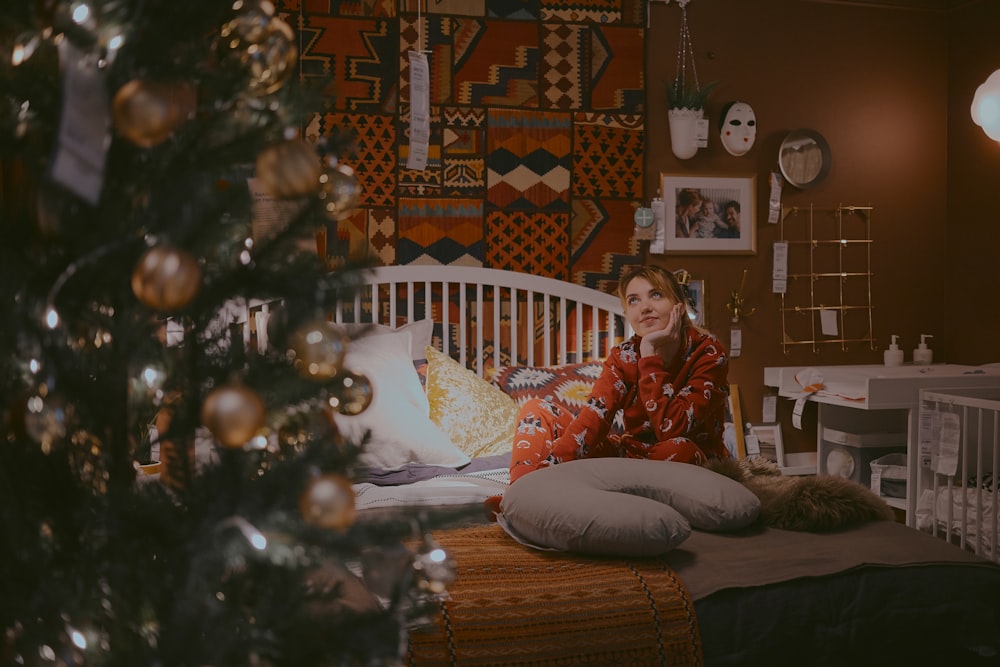 Frau sitzt auf dem Bett in der Nähe des Weihnachtsbaums