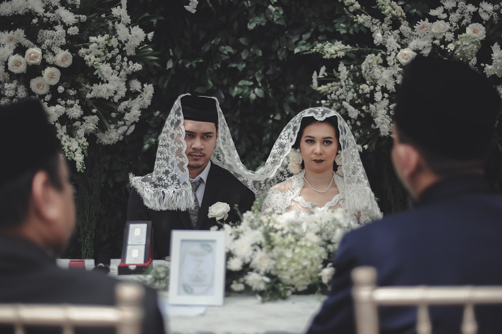 sitting man and woman with white veil on top of their heads