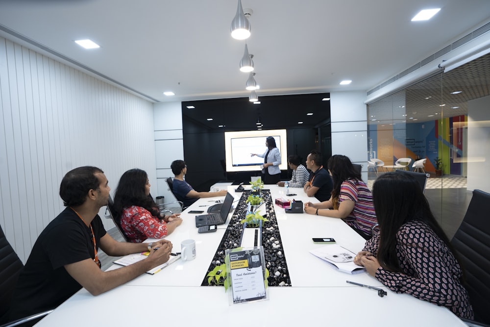 people sitting at the table looking to another person standing in front of them