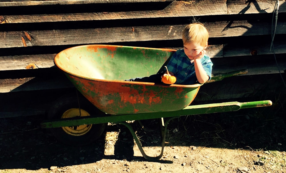 boy riding green wheelbarrow