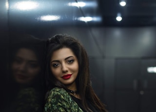 woman in green camouflage jacket leaning on wall