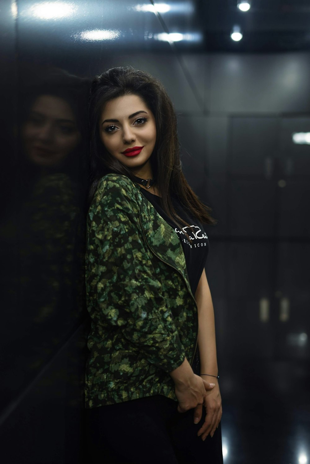 woman in green camouflage jacket leaning on wall