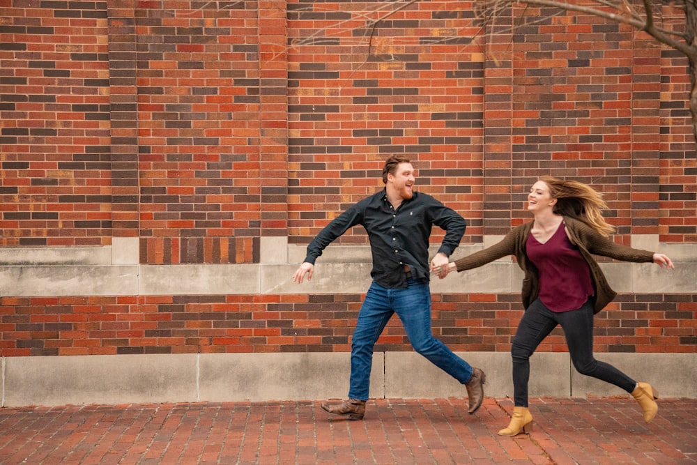 man holding woman while running near wall