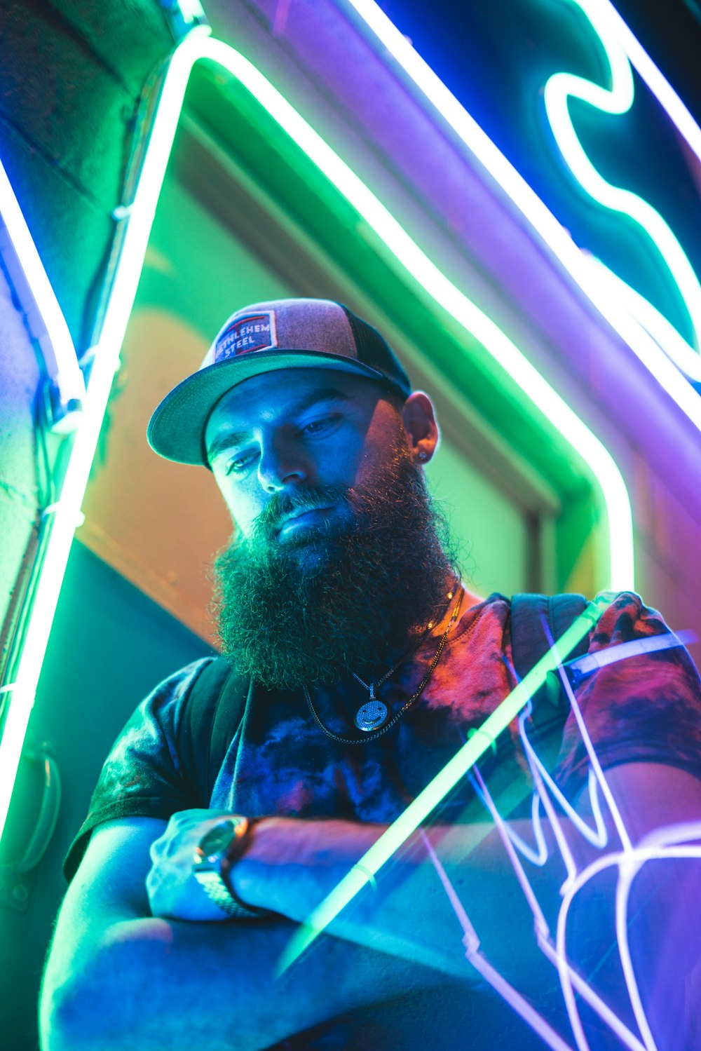 low-angle photography of a bearded man beside a green neon light signage