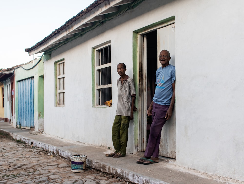 two men leaning on wall in front of door