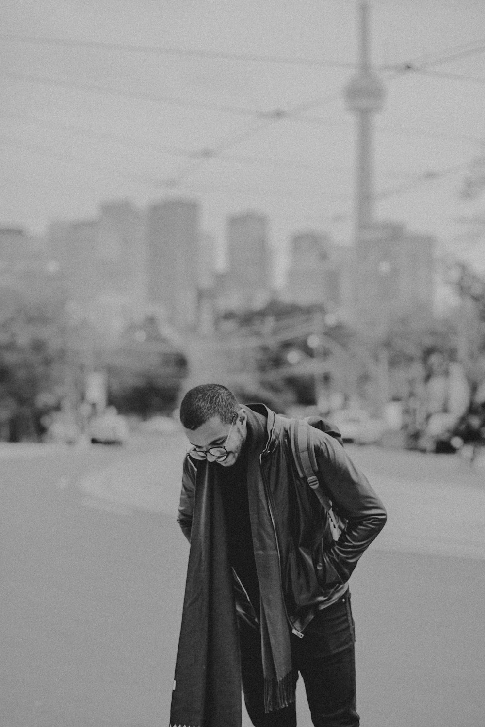 grayscale photo of man wearing jacket and scarf facing down