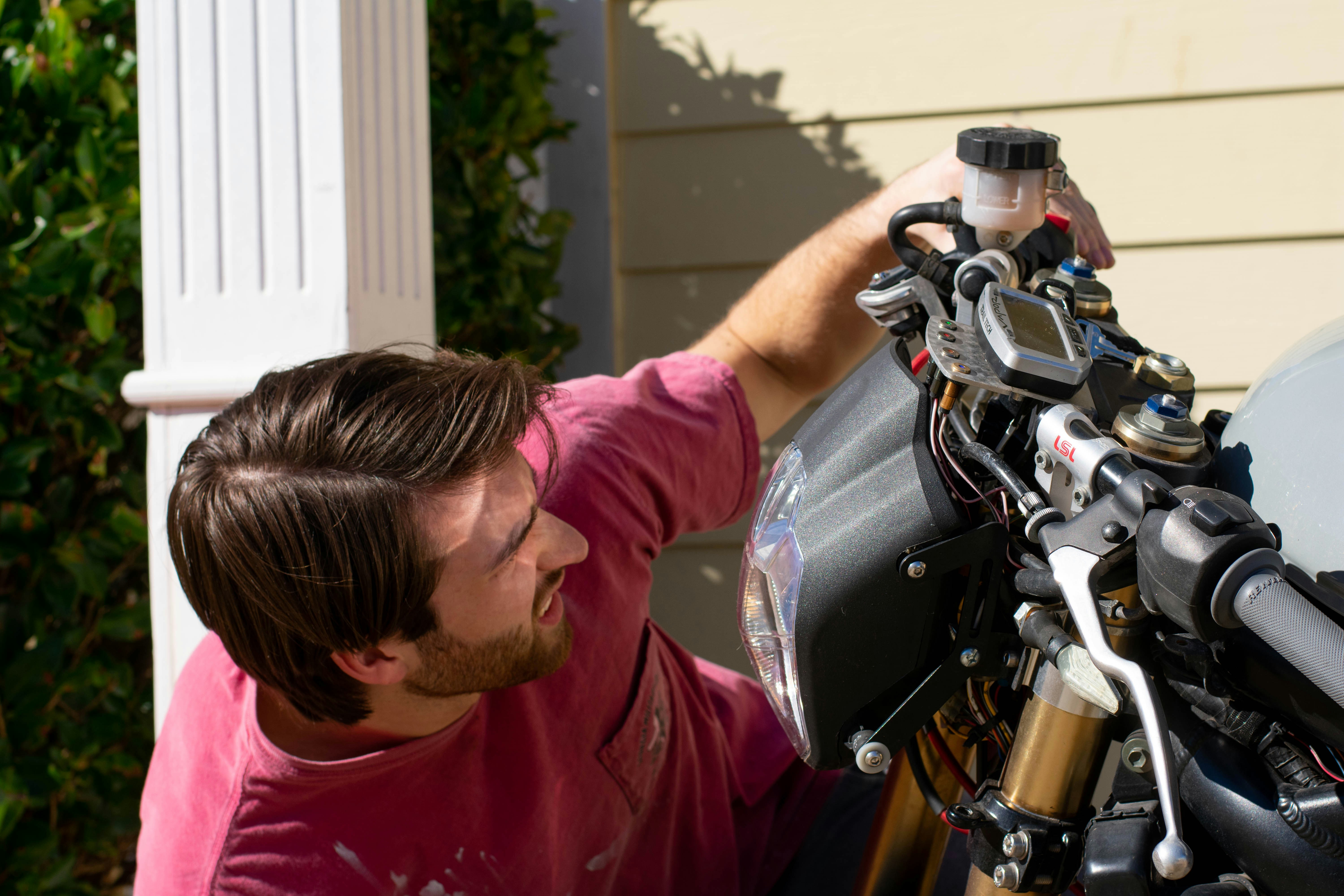 shallow focus photo of man looking at motorcycle headlight