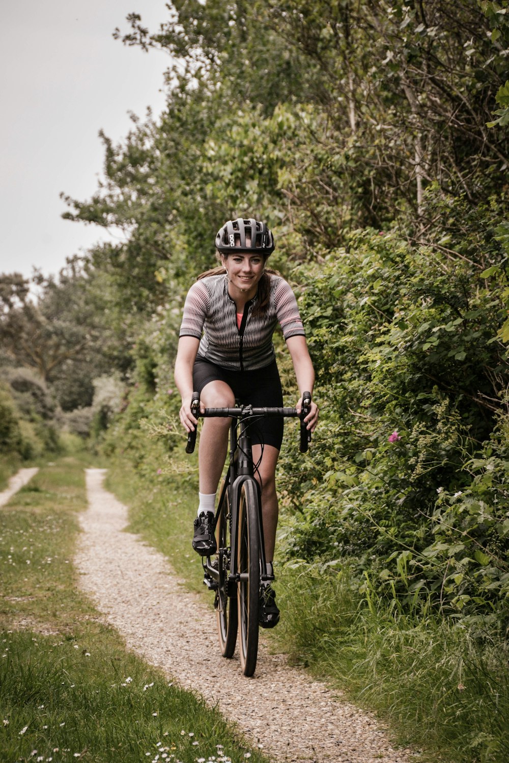 woman riding road bike on dirt road during day