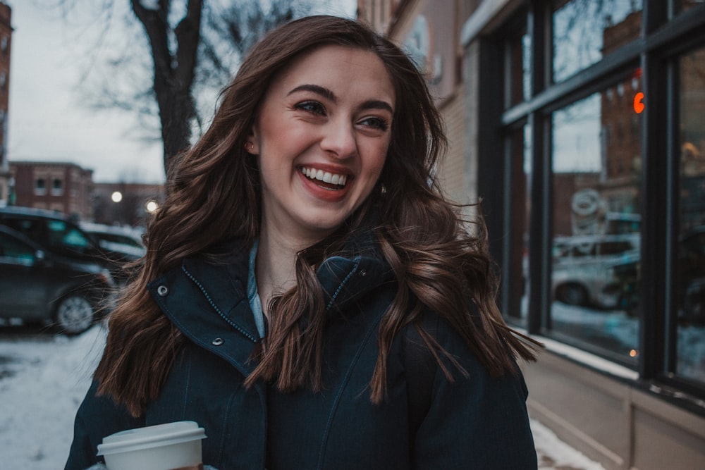 a smiling woman holding a cup of coffee