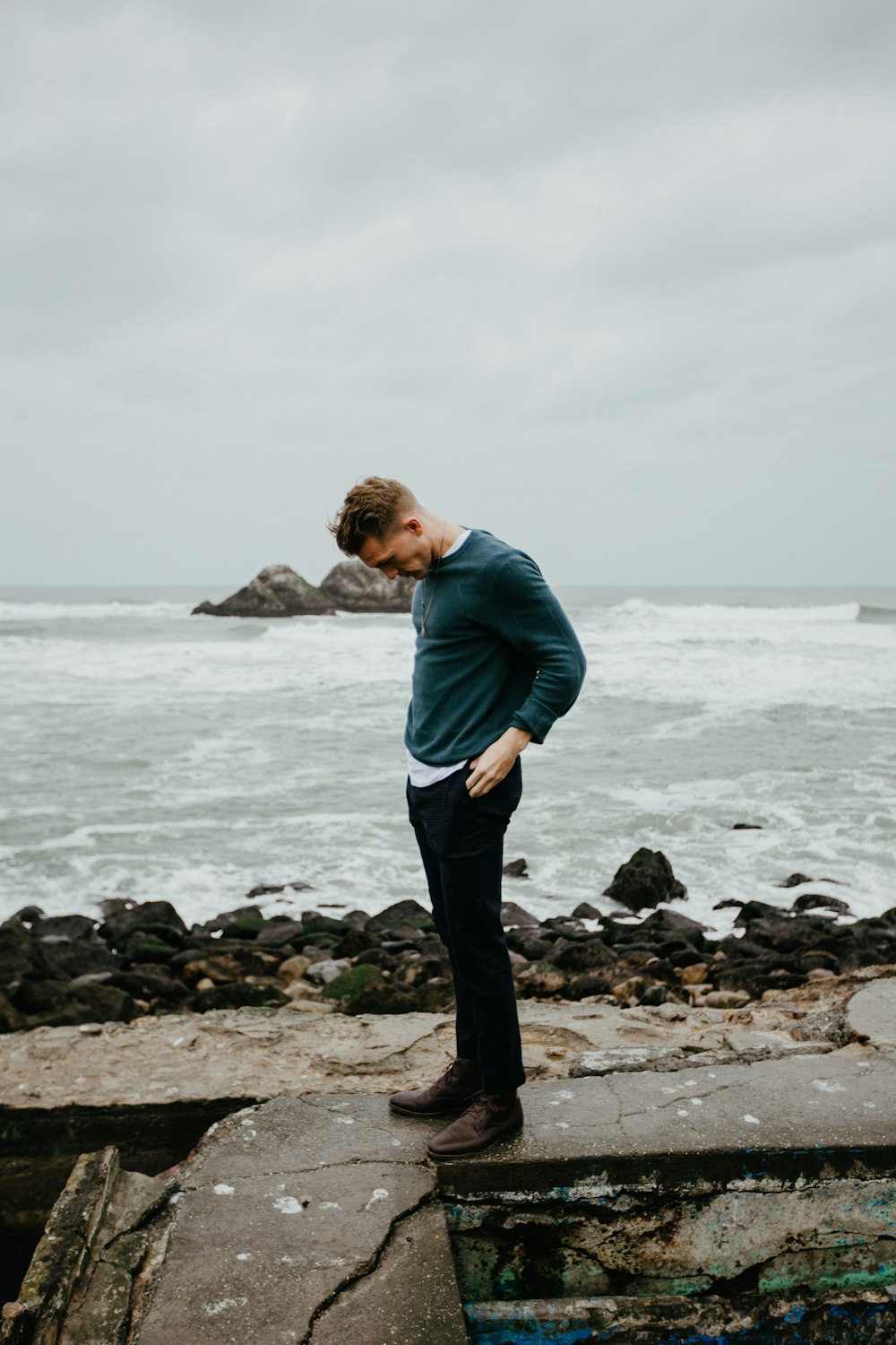 man wearing blue sweater standing on the seashore